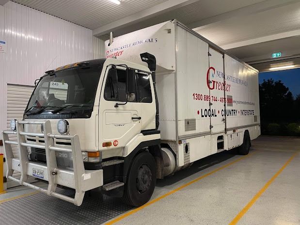 White box truck parked indoors in a loading bay tunnel, with a silver front bumper guard.