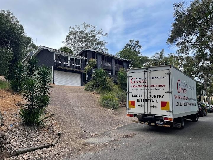 Moving truck on a steep driveway outside a dark house with a garage.