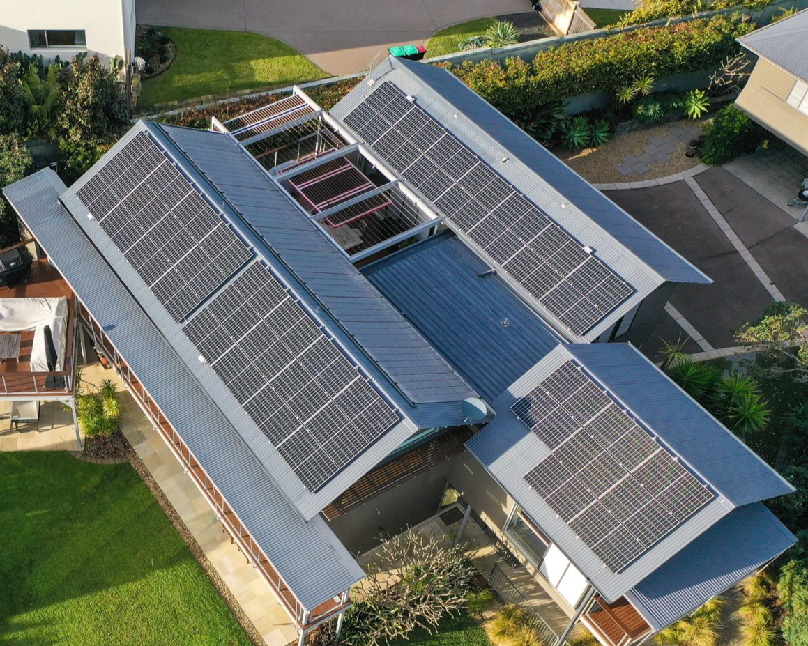 Aerial view of a building roof covered with solar panels in a residential area