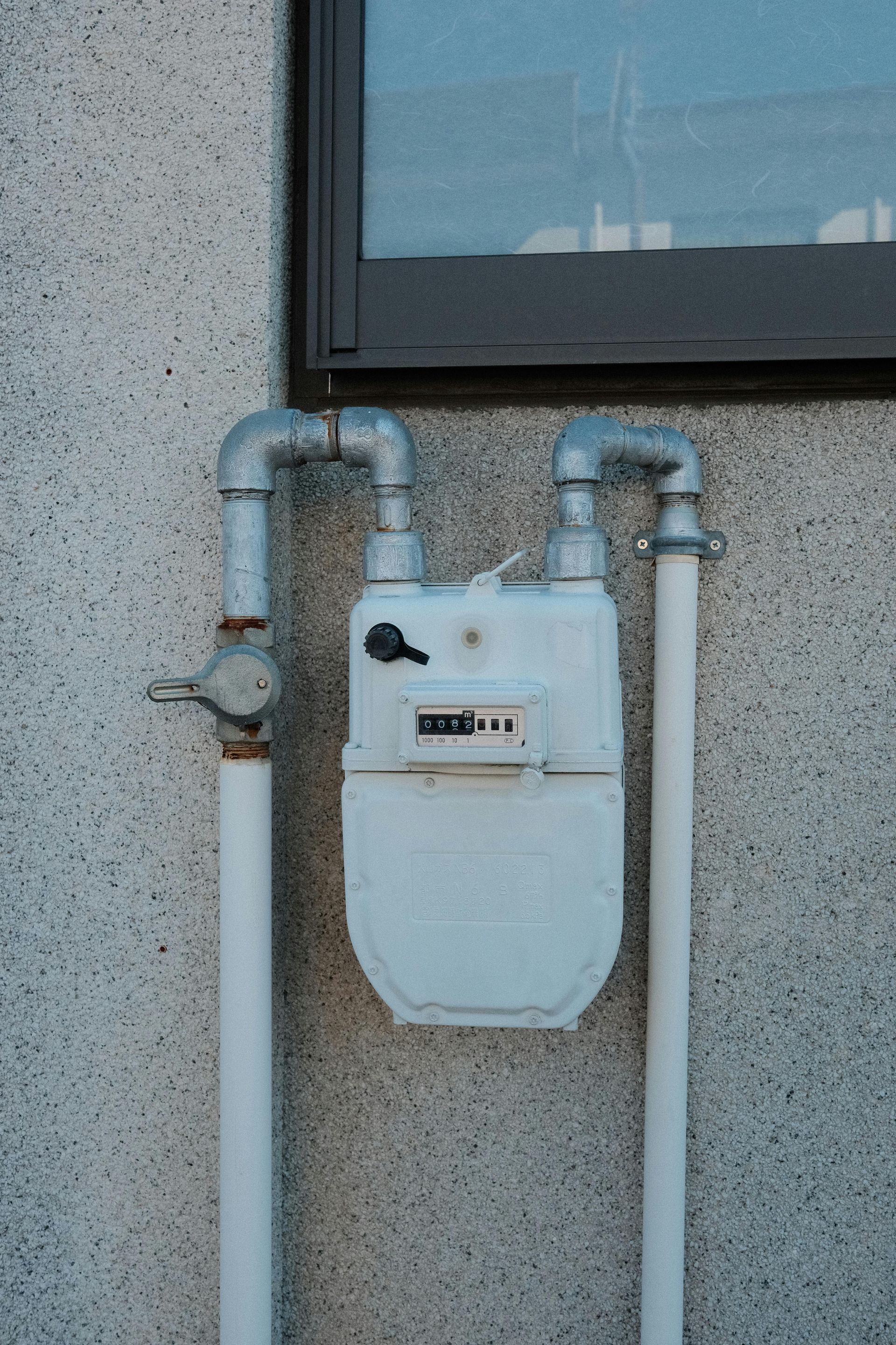 Commercial gas line repair on a wall-mounted gas meter with silver plumbing pipes.