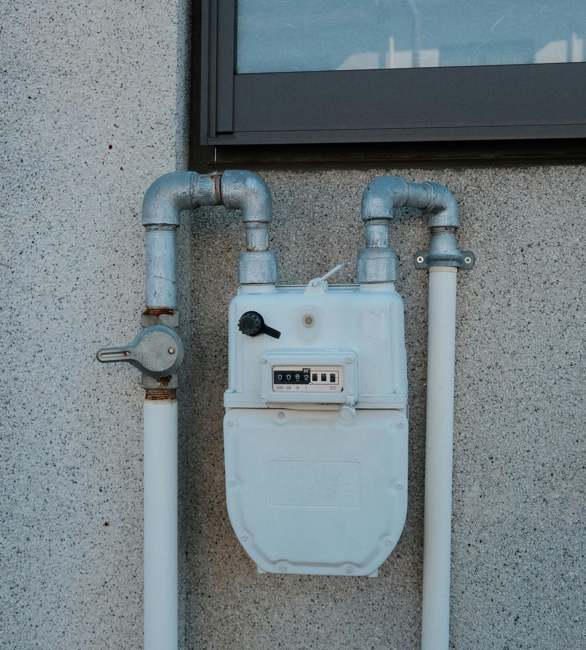 Commercial gas line repair on a wall-mounted gas meter with silver plumbing pipes.