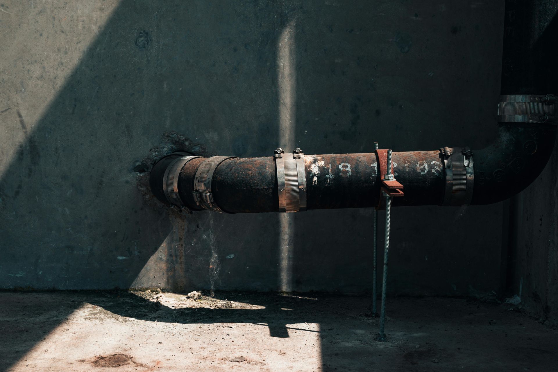 A close-up of a rusty sewer line in a room.