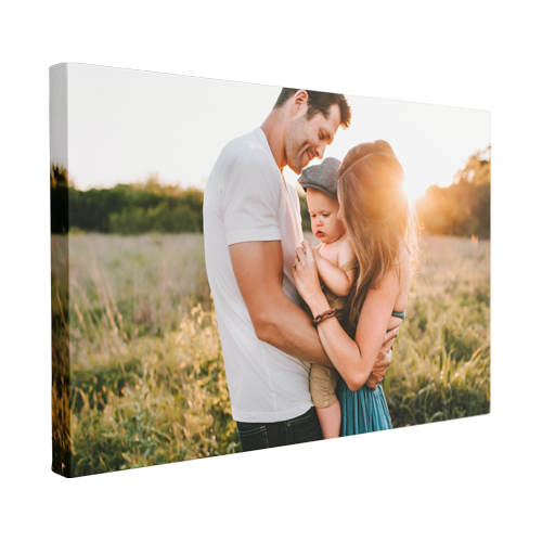 A man and woman are holding a baby in a field.