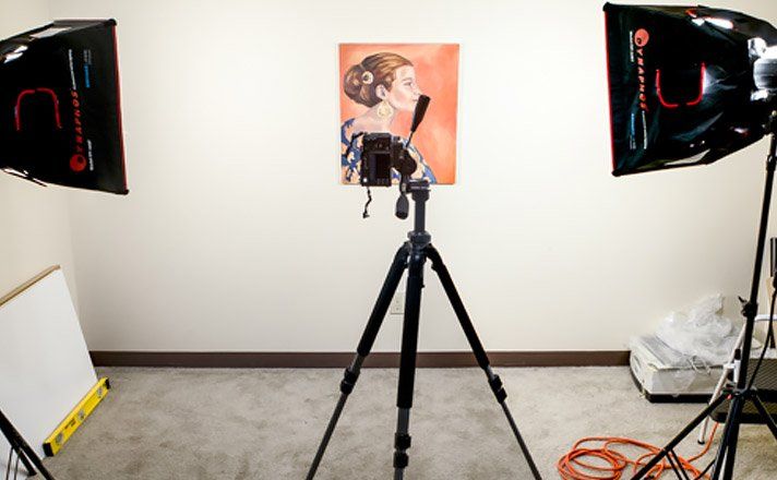 A camera on a tripod in front of a painting