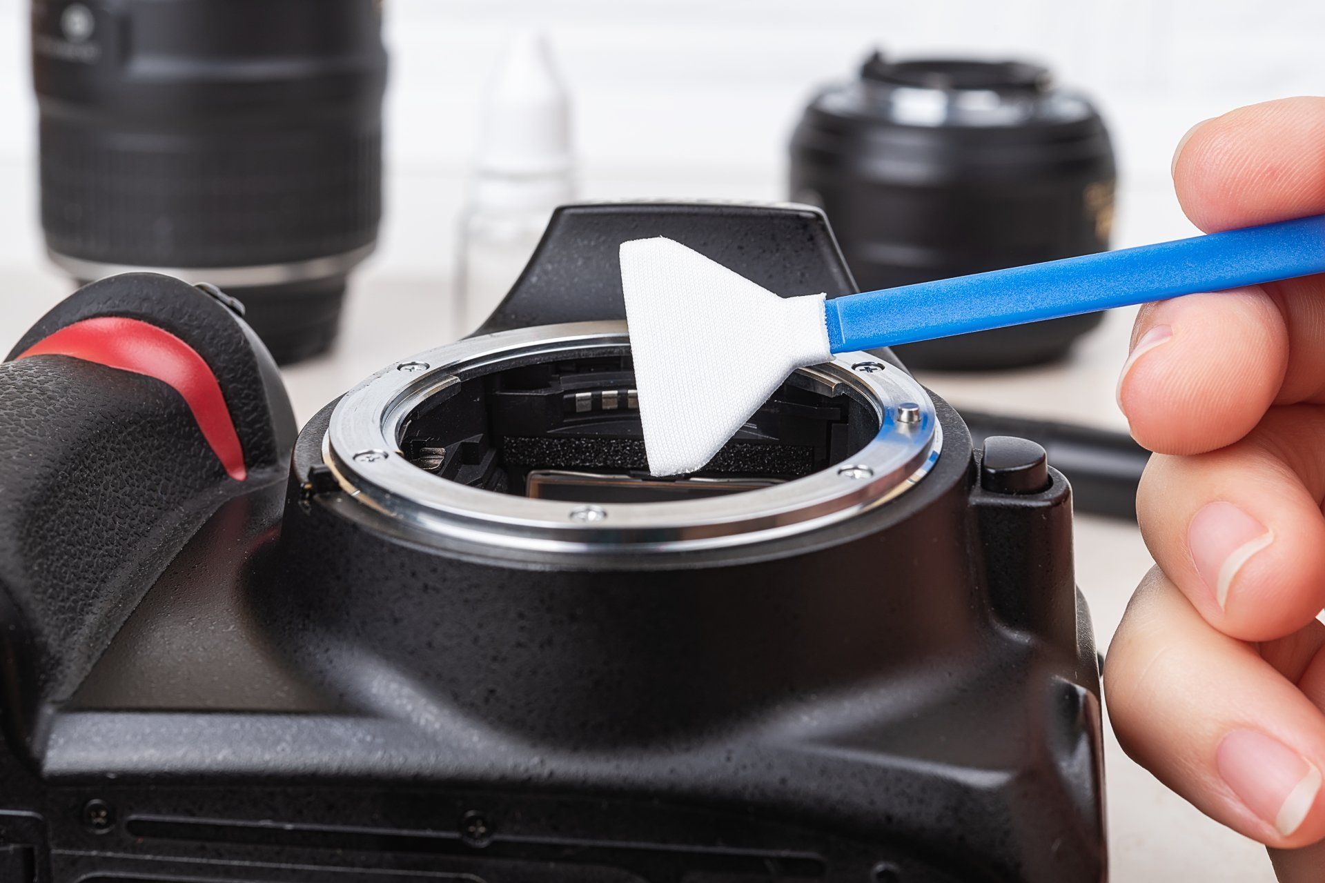 A person is cleaning a camera with a brush.
