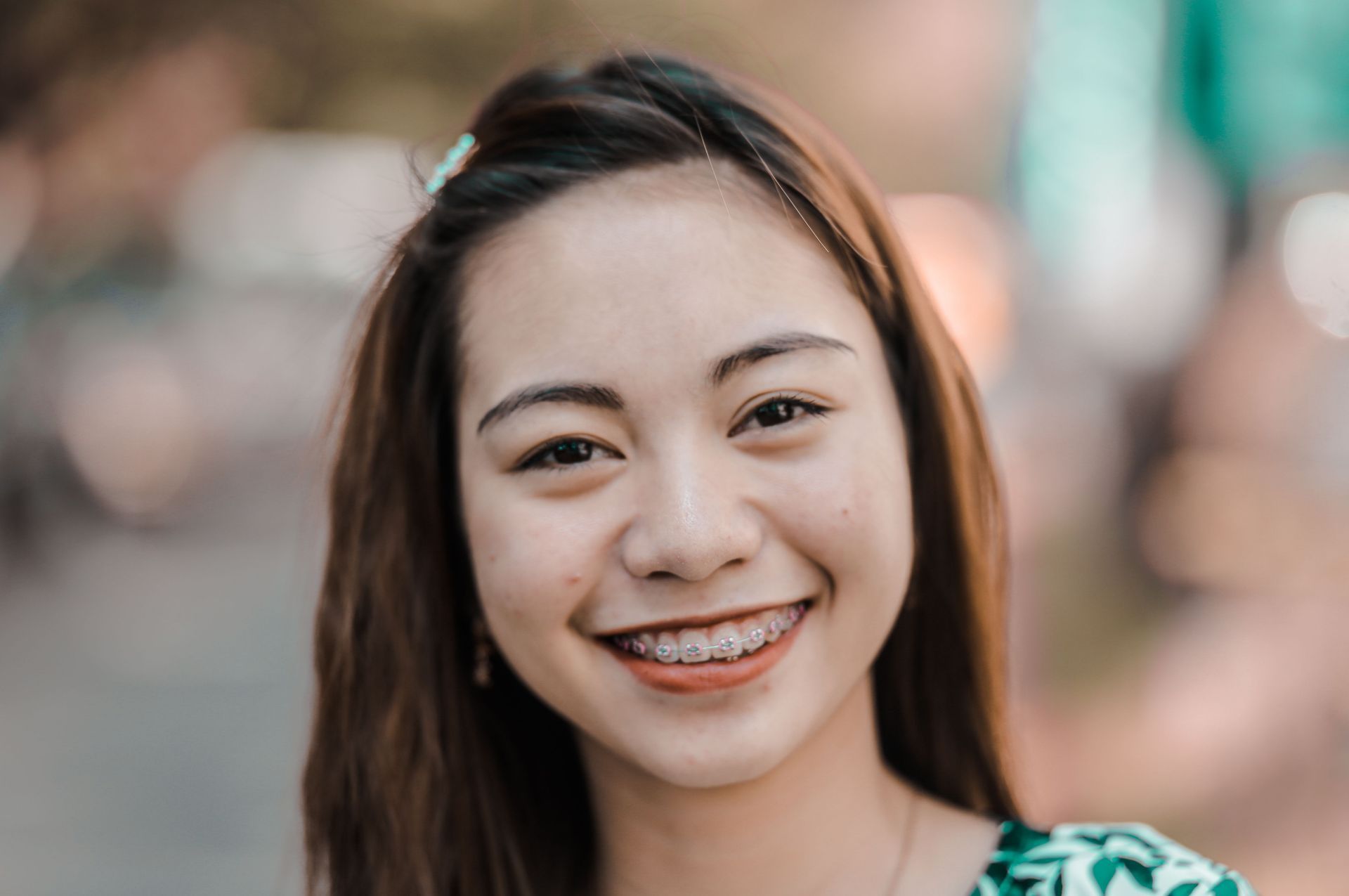 Woman with brown hair and braces smiling and showing her braces towards the camera