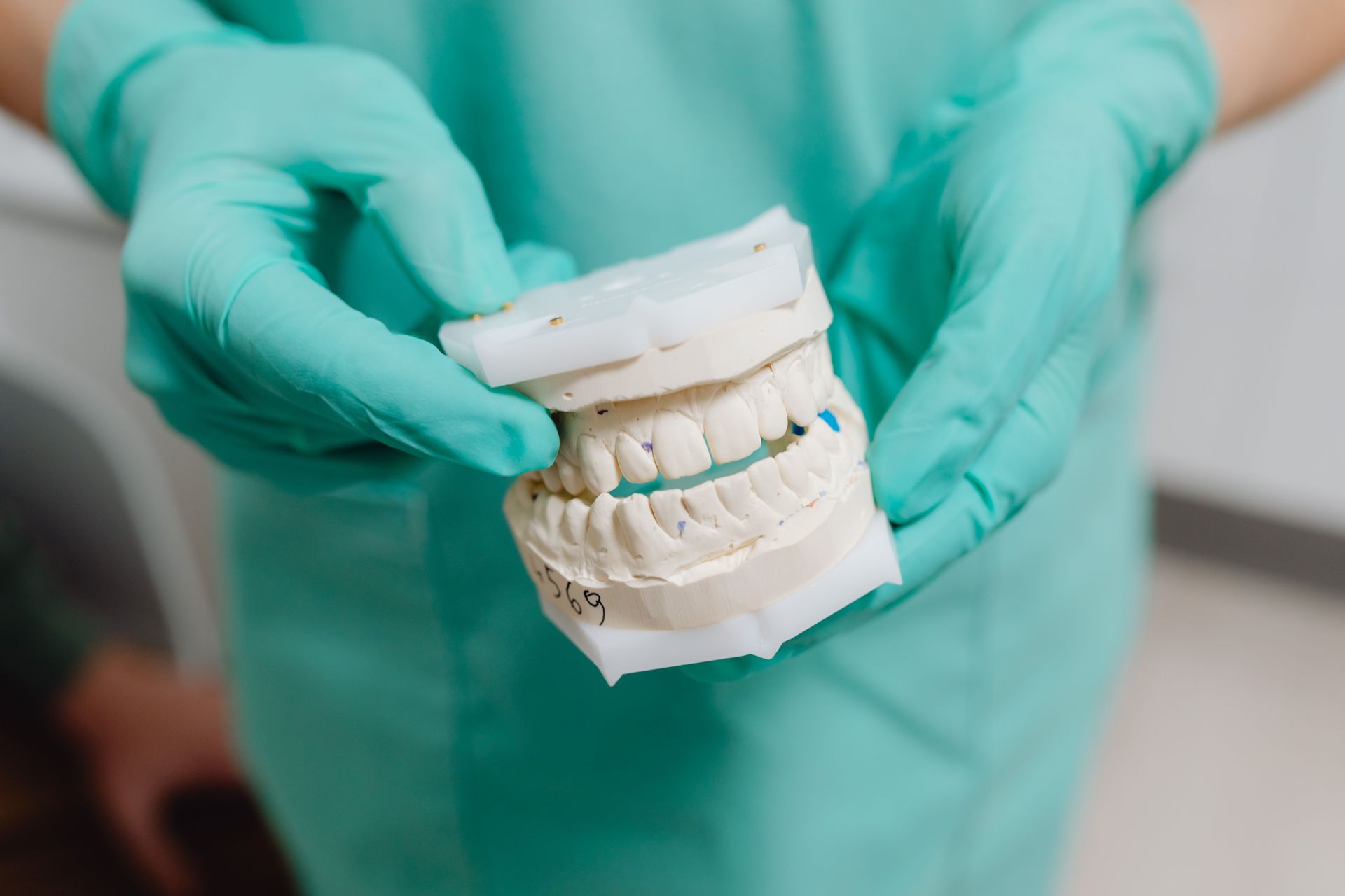 Gloved hands holding a dental mold of upper and lower teeth