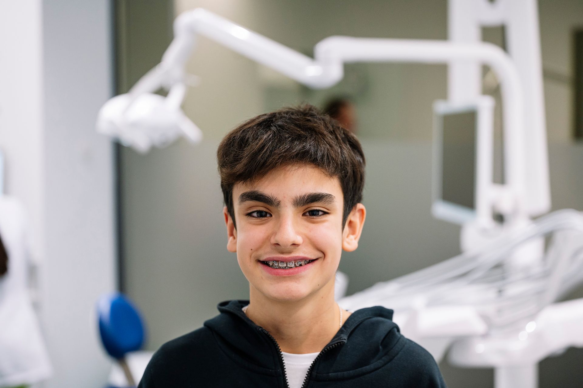 Teen smiling in a dental clinic with equipment in the background