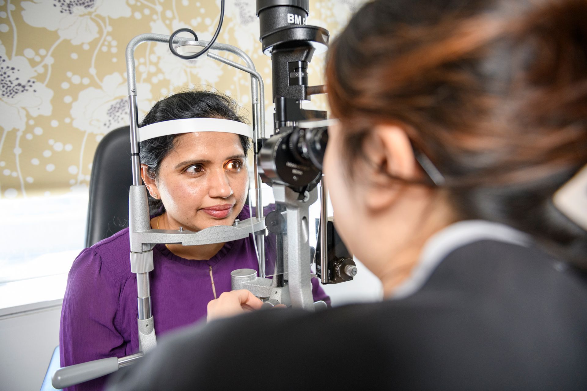 Woman undergoing eye exam with an ophthalmoscope.