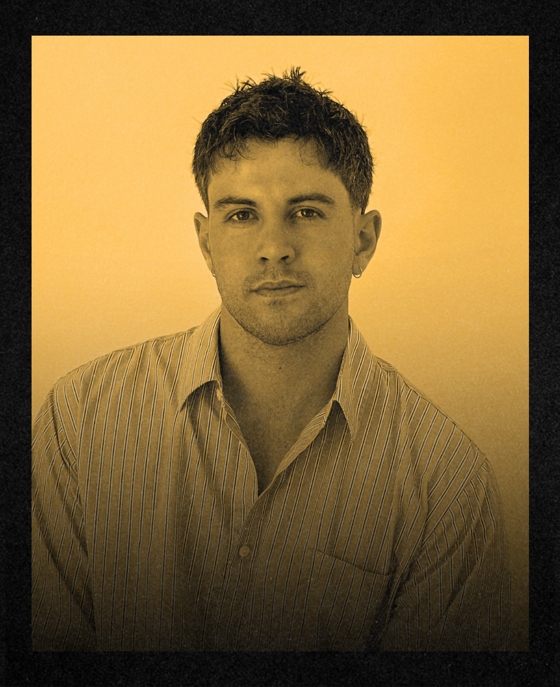 Black-and-white portrait of a person with short curly hair wearing a white collared shirt, looking at the camera