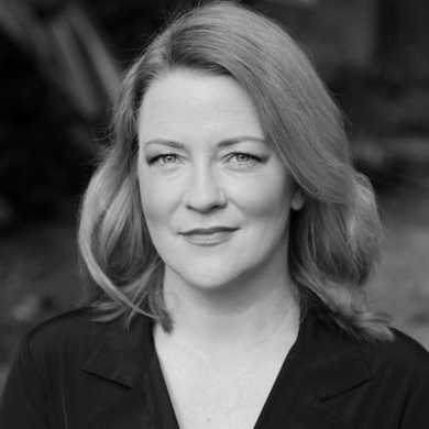 Black-and-white portrait of a woman with long blonde hair and large glasses, facing the camera.