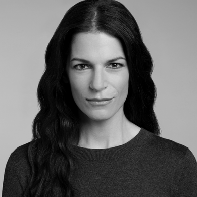 Black-and-white portrait of a person with long dark hair wearing a dark sweater