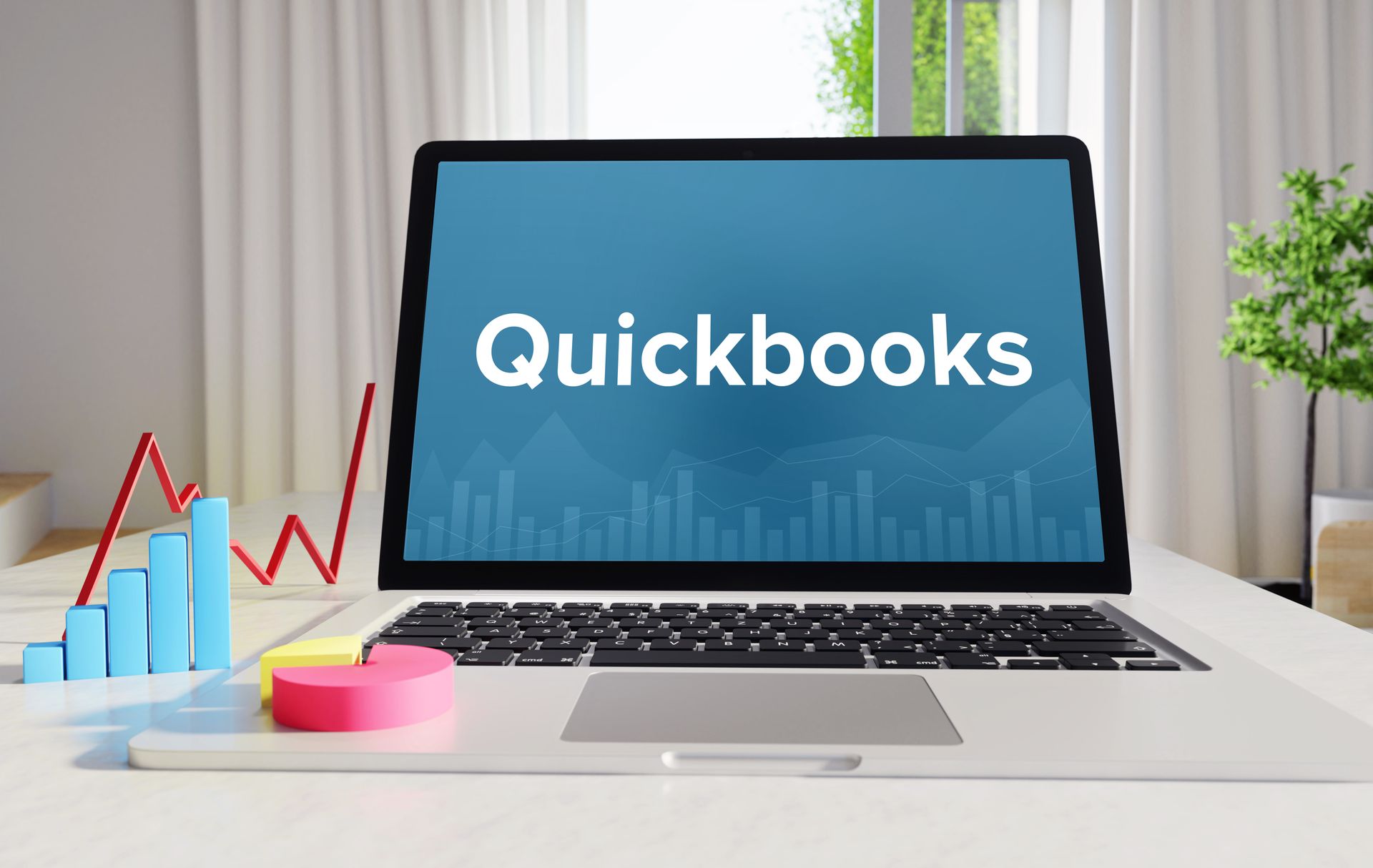 Laptop displaying QuickBooks software with business charts on a desk.