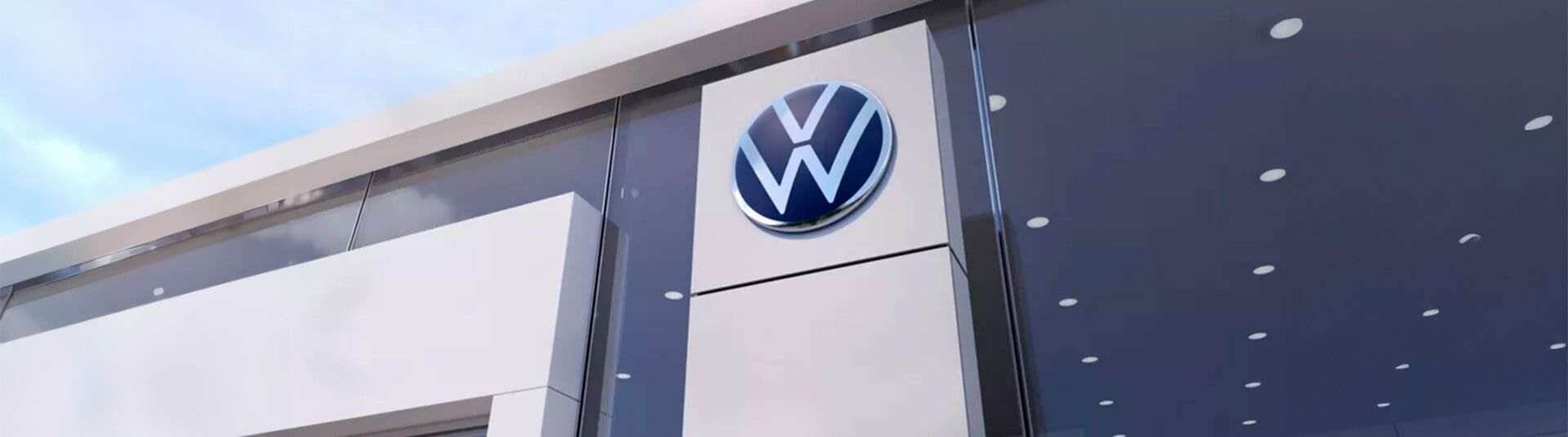 Placa de concessionária Volkswagen na fachada de um prédio com detalhes em azul e branco.
