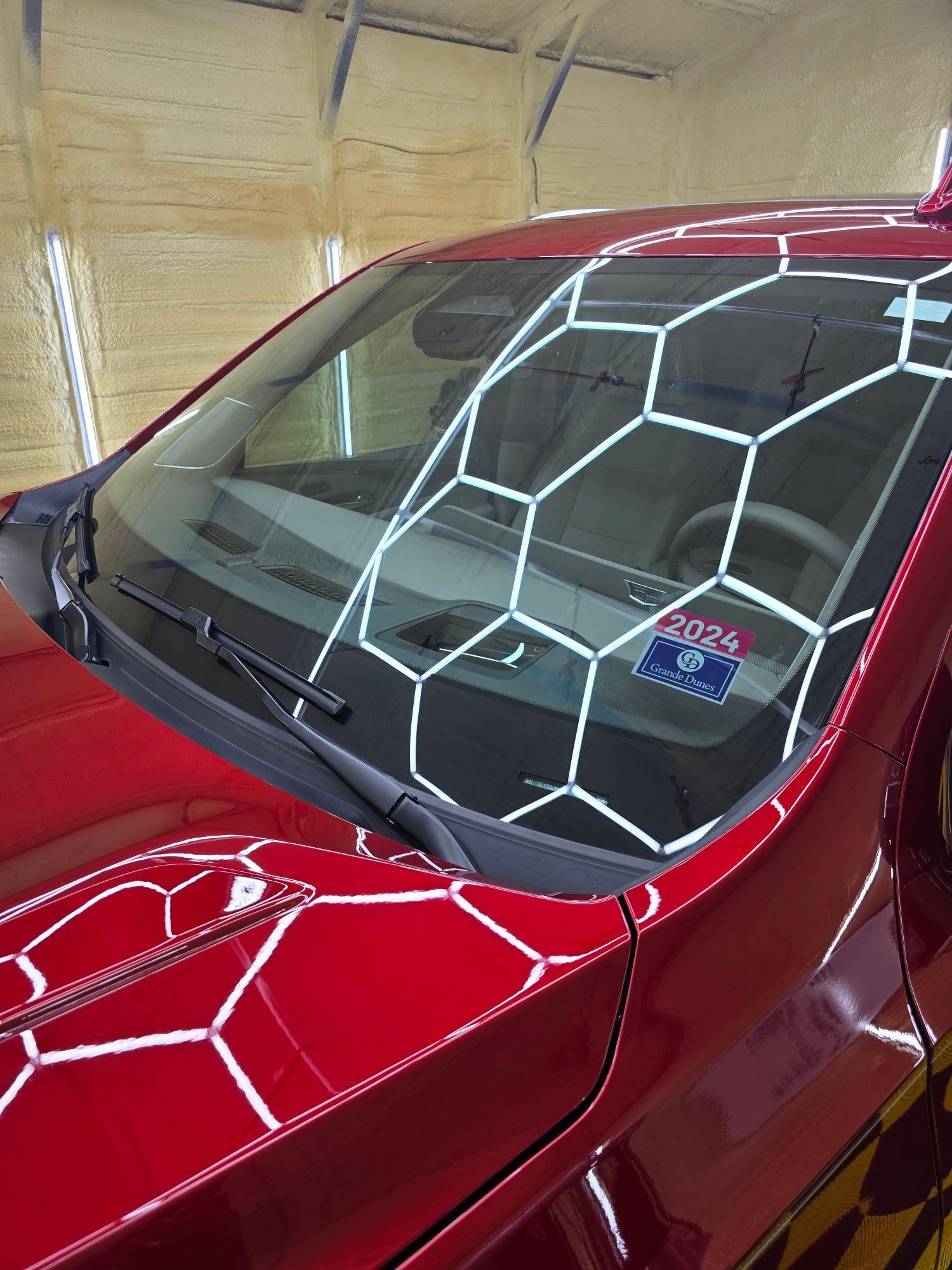 A red car with a sticker on the windshield that says 50724