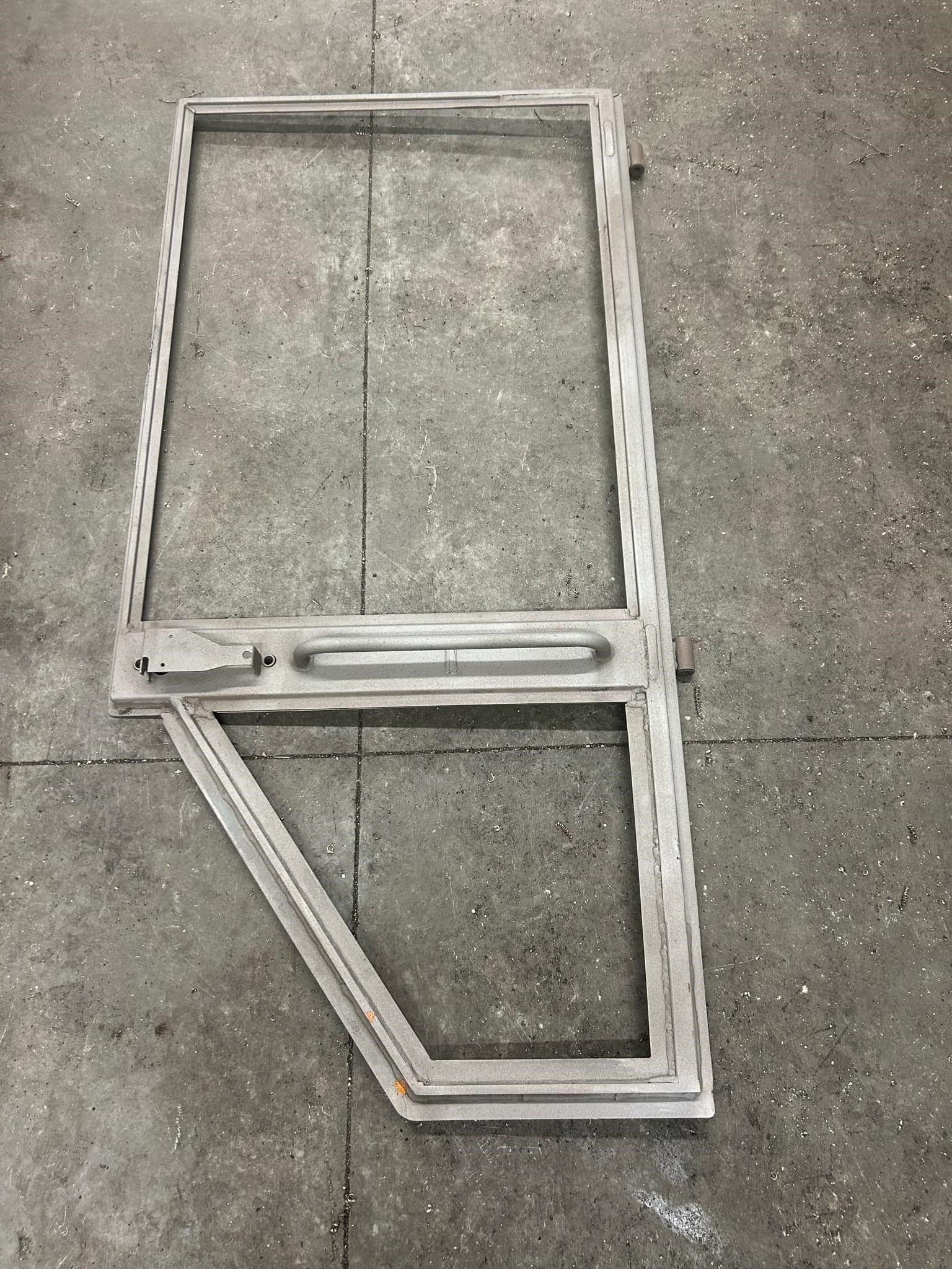 A metal frame with a glass window is sitting on a concrete floor.