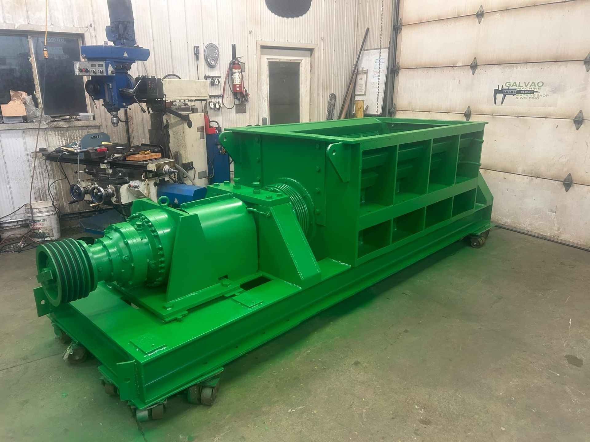 A green machine is sitting in a garage next to a garage door.