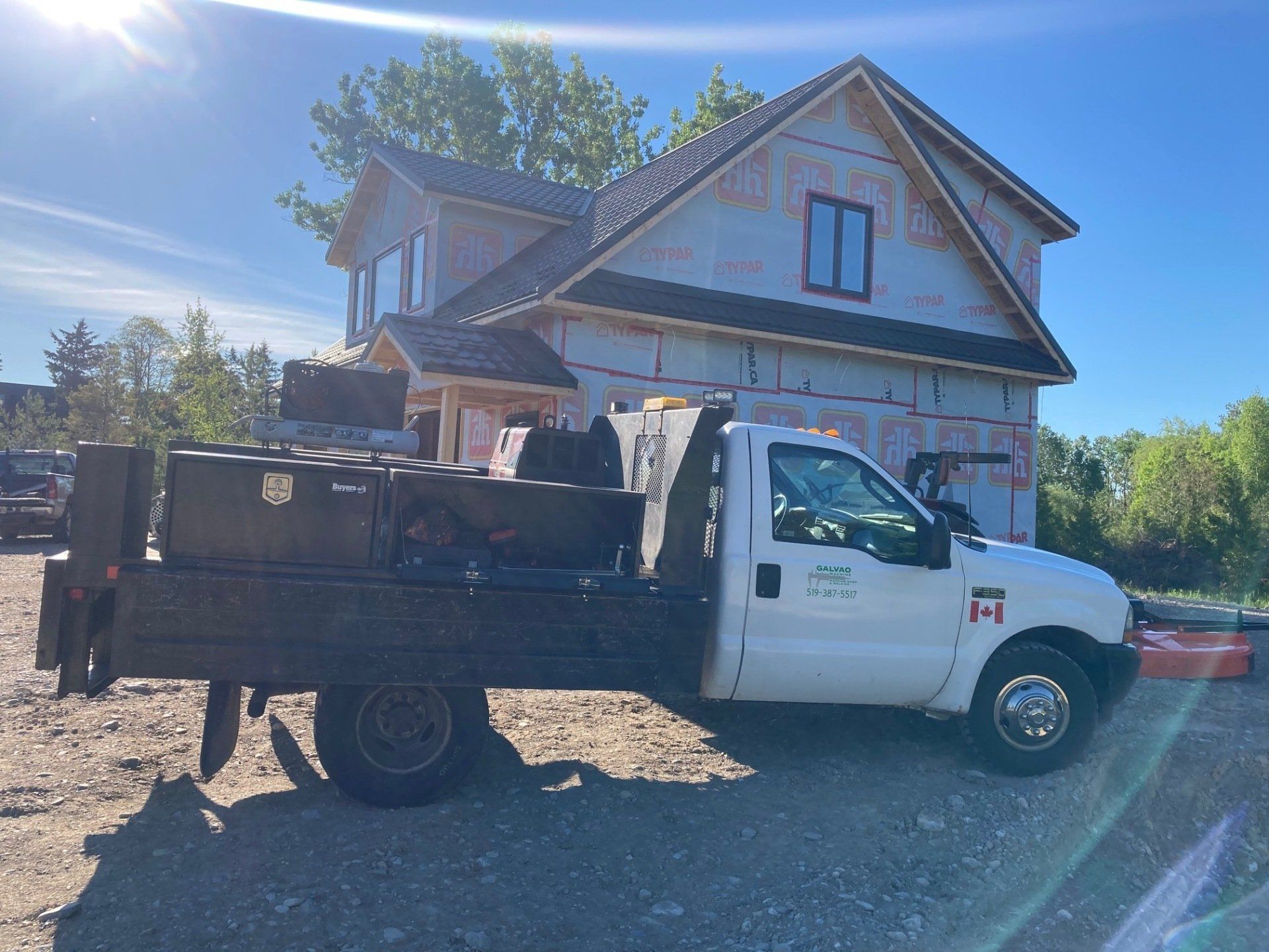 A white truck is parked in front of a house under construction.