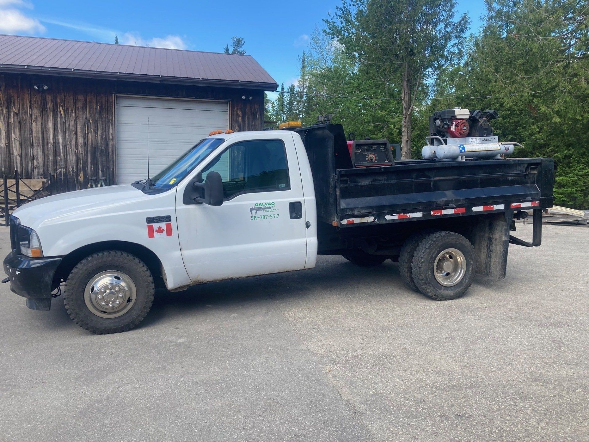 A white truck with a canadian flag on the side is parked in front of a garage.