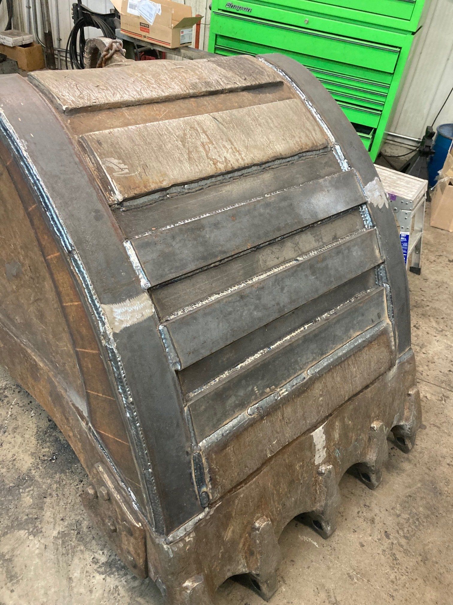 A large metal bucket is sitting on the ground in a garage.