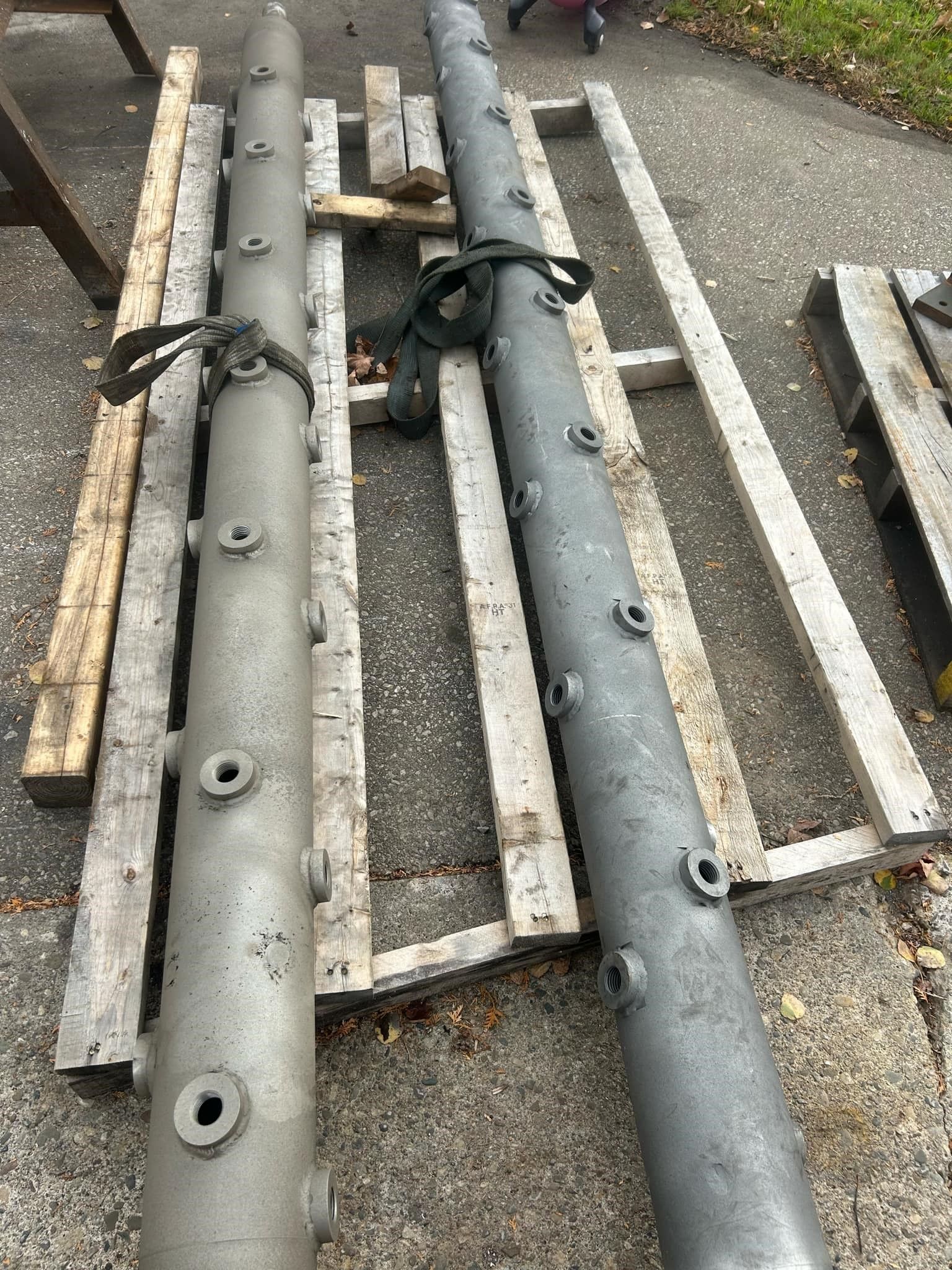 A large metal pipe is sitting on top of a wooden pallet.