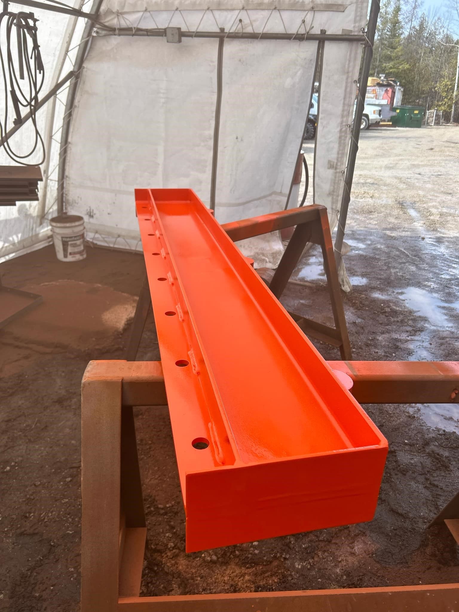A long orange piece of metal is sitting on a wooden table.