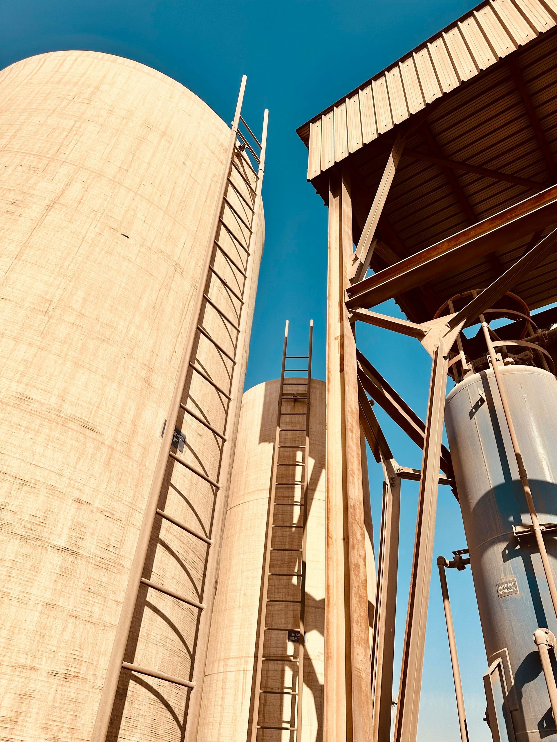 Giant industrial excavator cutting into a pile of earth; sunny day, background windmills.