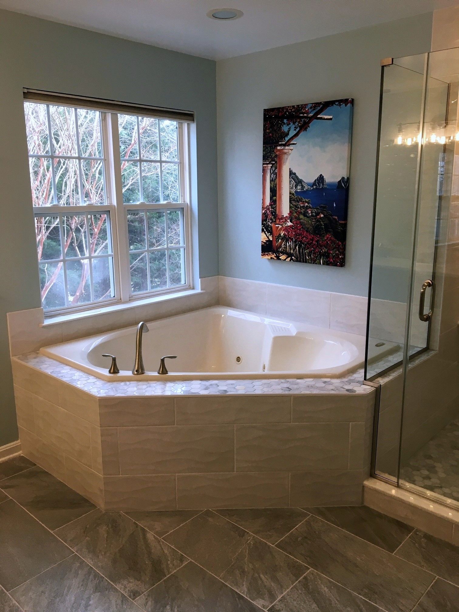 Bathroom with corner soaking tub, glass shower, window, and framed wall art
