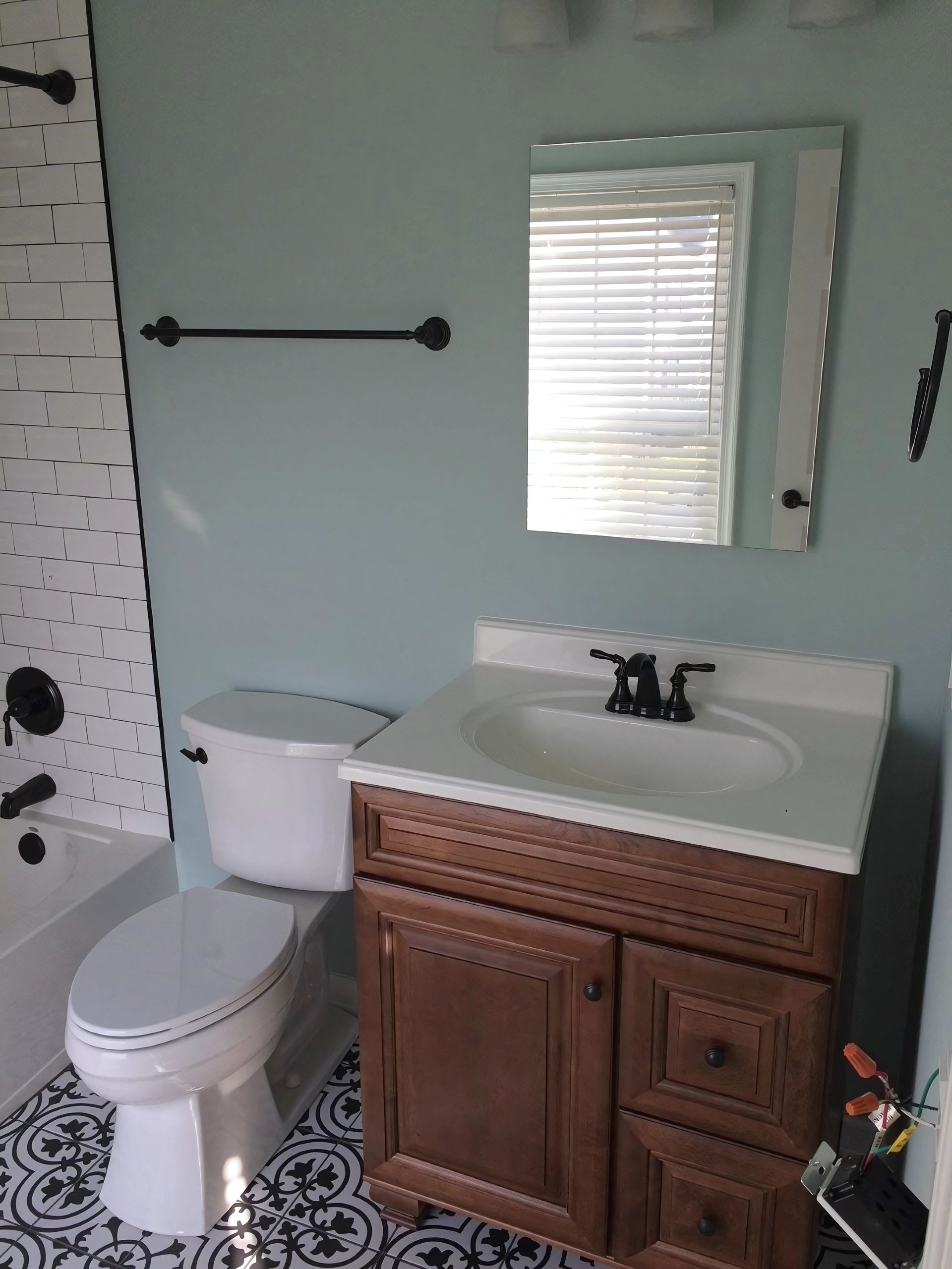 A bathroom with a toilet, sink, mirror and white bathtub.