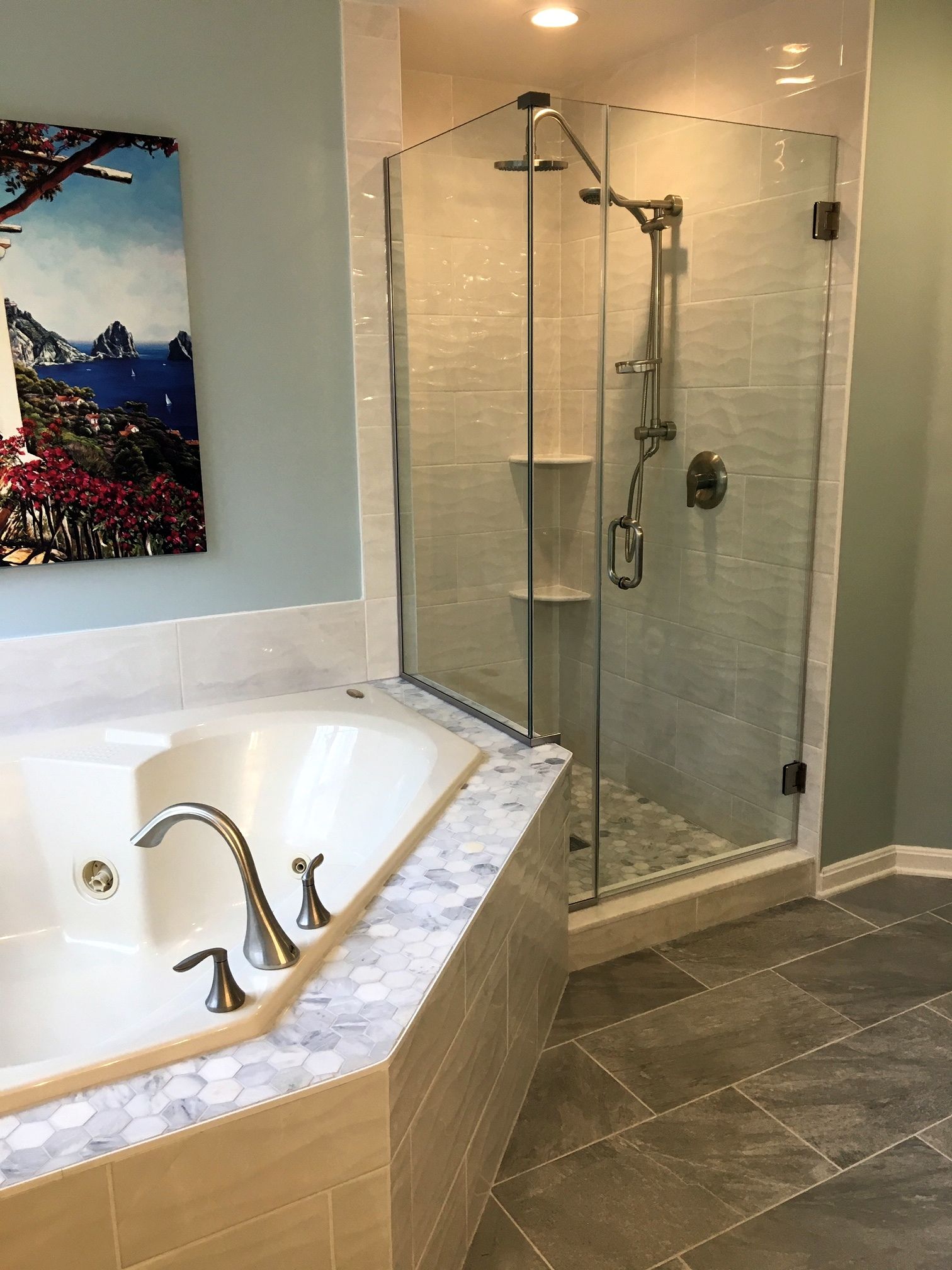 Bathroom with white tub, glass walk-in shower, and gray tile floor.