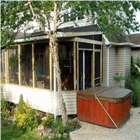 A screened in porch with a hot tub in front of it.