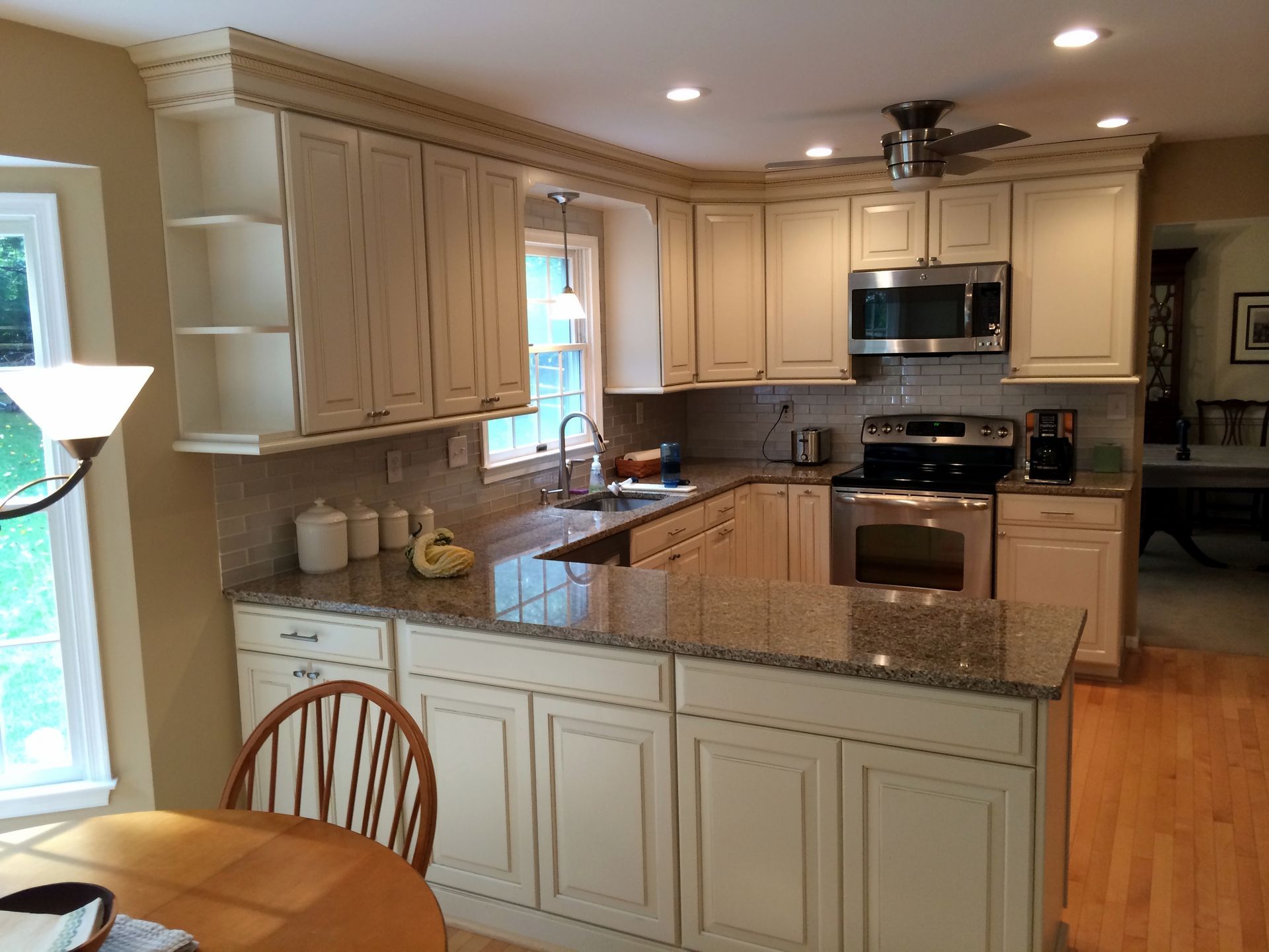 Bright kitchen with cream cabinets, granite countertops, island, stainless steel appliances, and a window by the sink