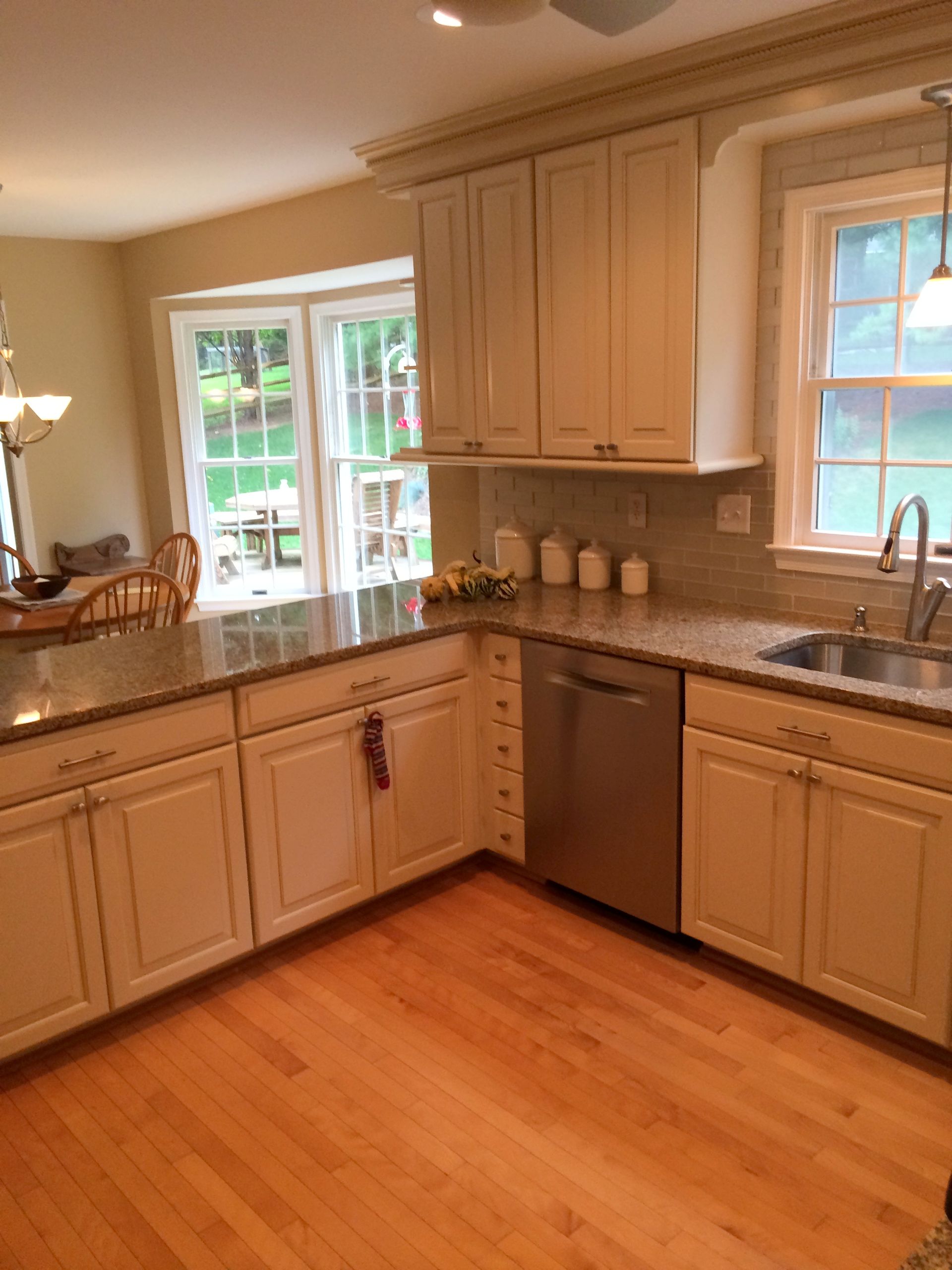 Bright kitchen with beige cabinets, granite counters, hardwood floor, and two windows letting in natural light