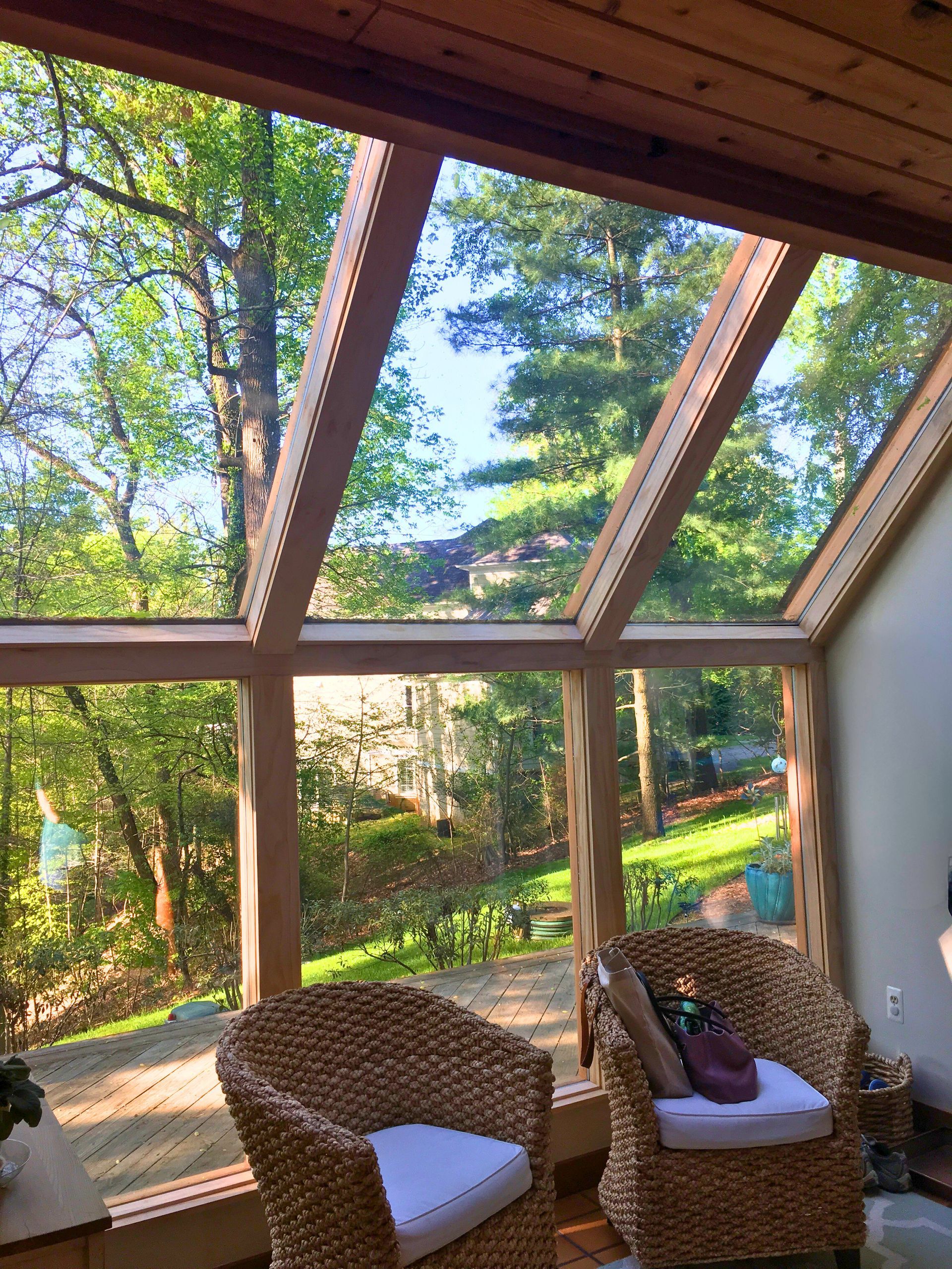 A sun room with wicker chairs and a view of trees