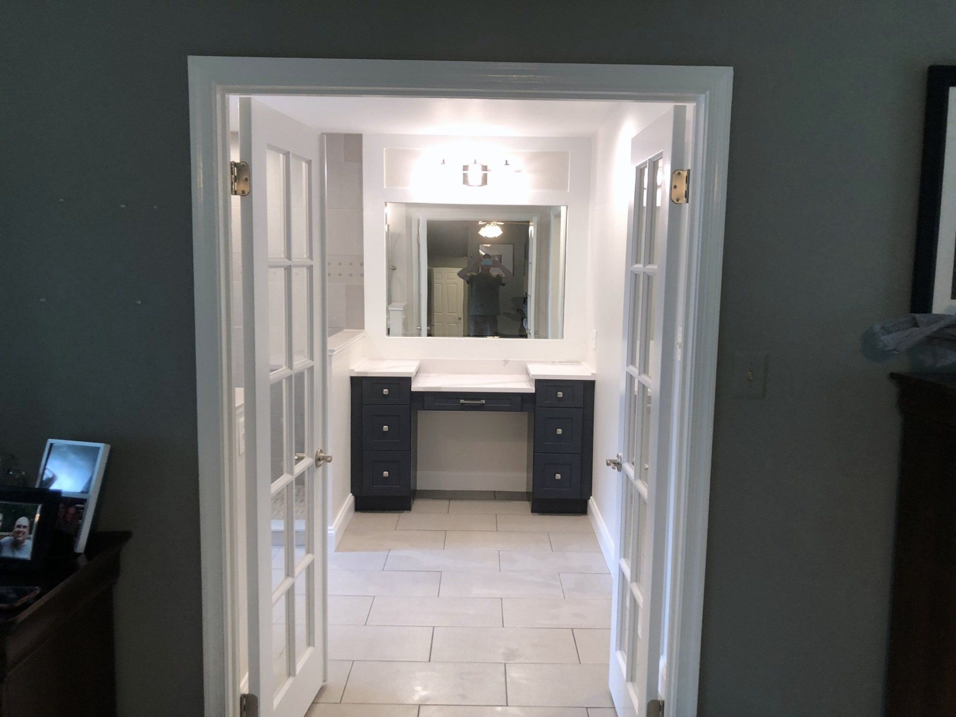 A hallway leading to a bathroom with a vanity and a mirror.