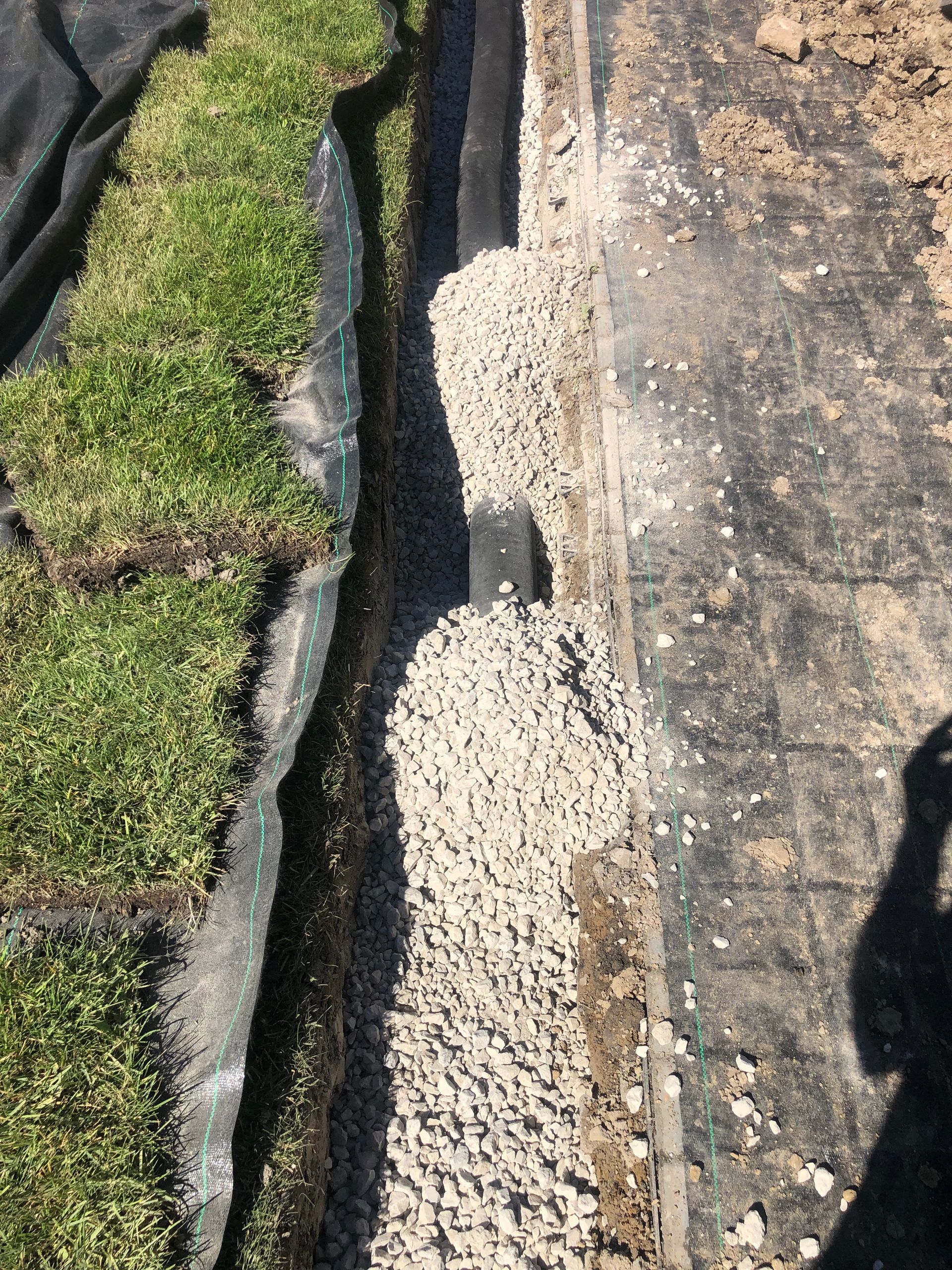 A person is standing next to a pile of gravel and grass.