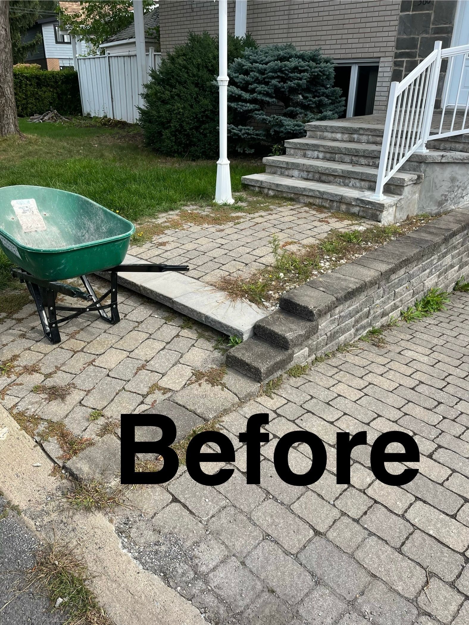A wheelbarrow is sitting on the sidewalk in front of a house.