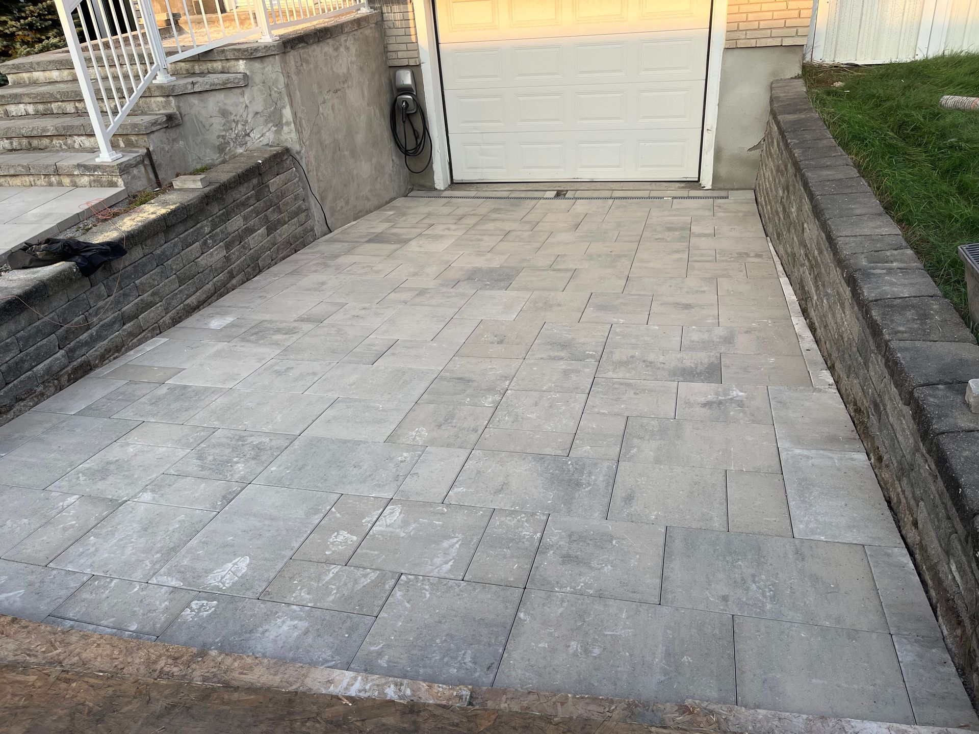 A brick driveway leading to a garage with stairs leading up to it.