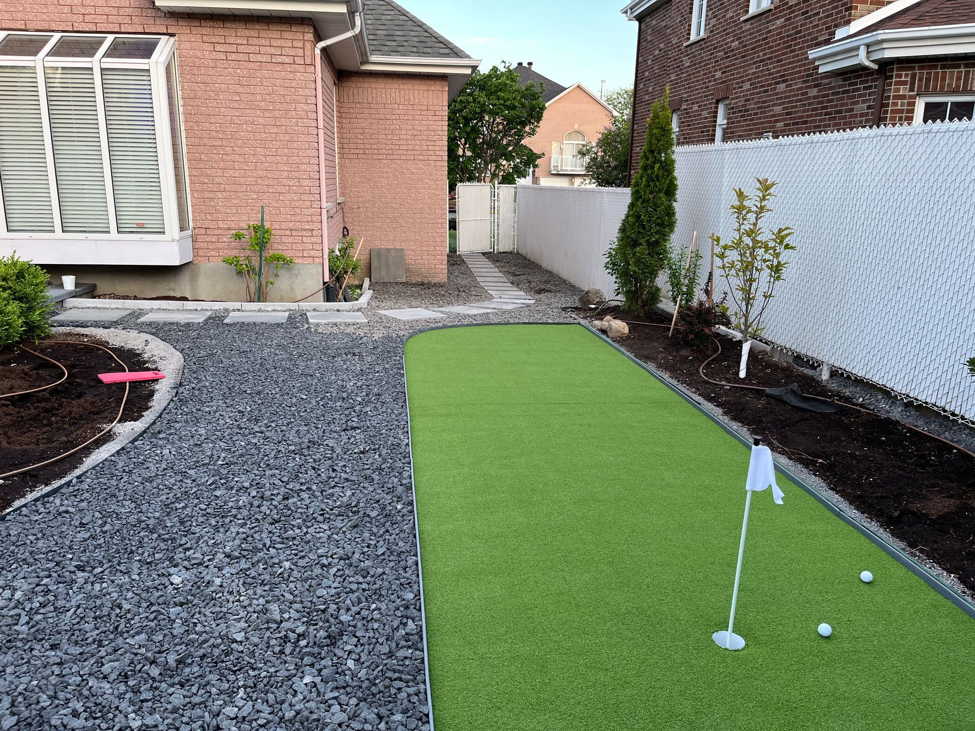 There is a putting green in the backyard of a house.