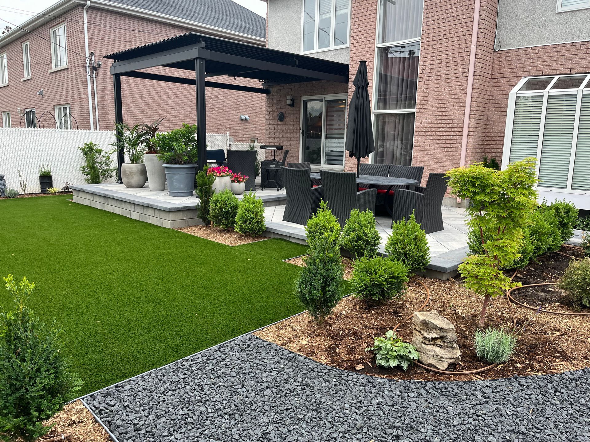A backyard with a pergola , patio , table and chairs.