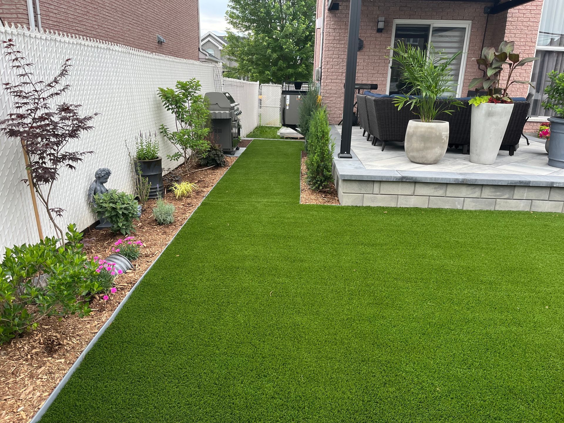 A backyard with a lush green lawn and potted plants.