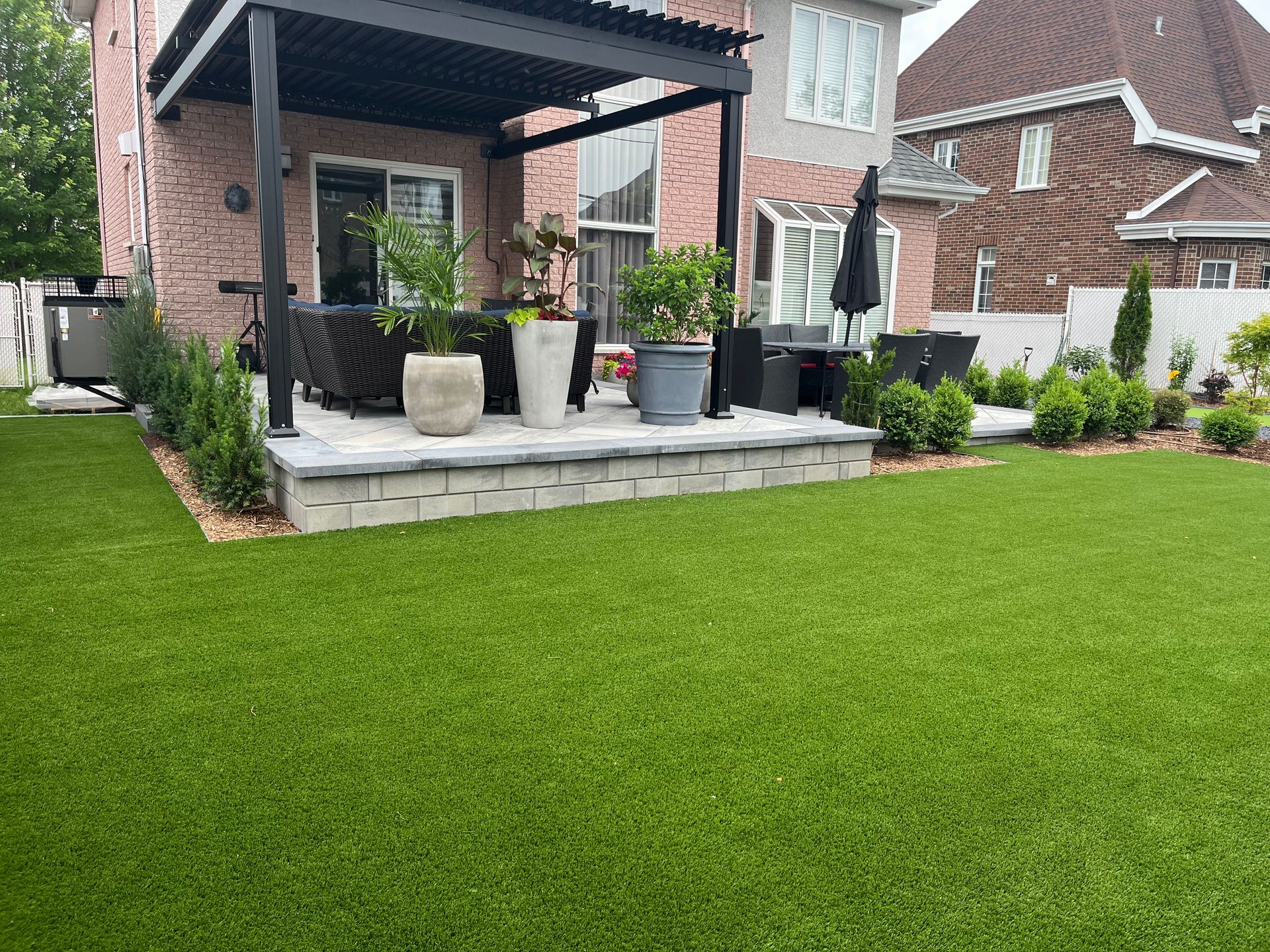 A backyard with a patio and a lush green lawn.