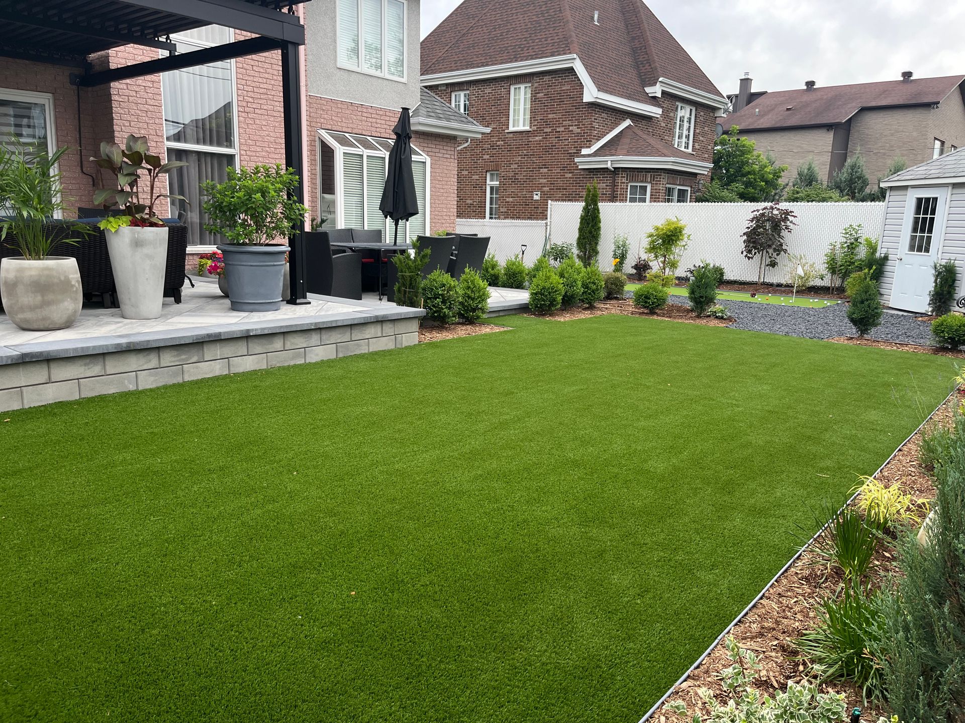 A backyard with a lush green lawn and potted plants.