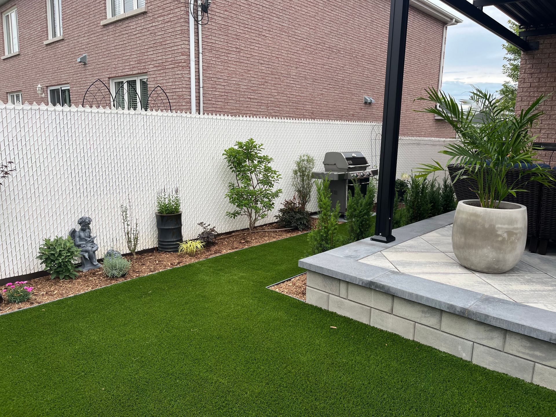 A backyard with a lush green lawn and a white fence.