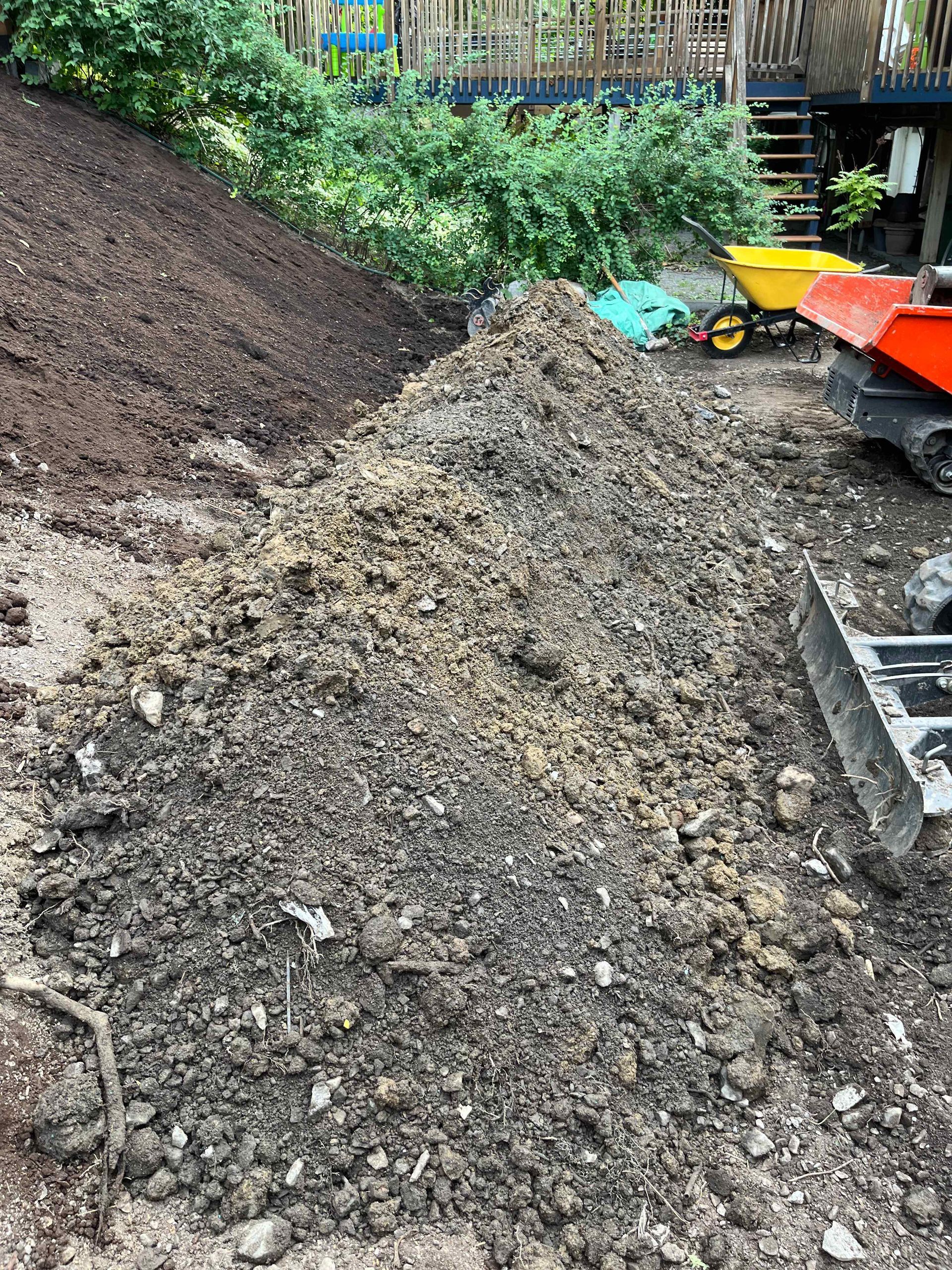 A pile of dirt is sitting on the ground next to a wheelbarrow.