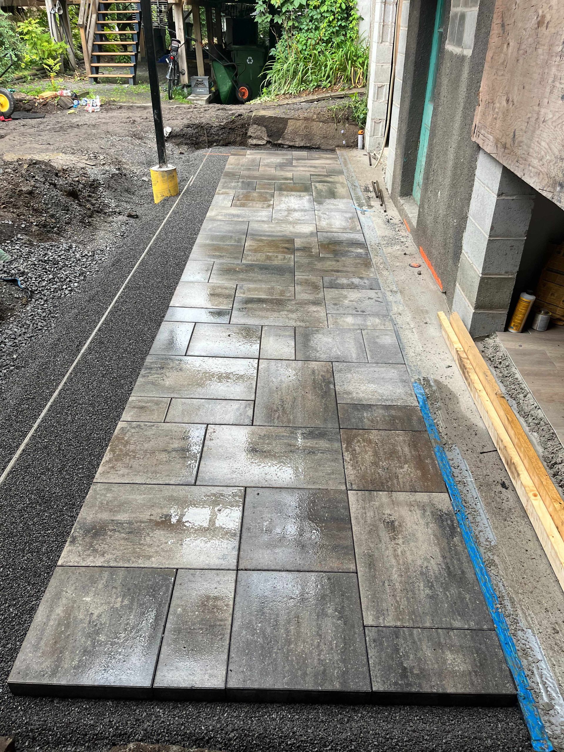 A stone walkway is being built in a backyard.
