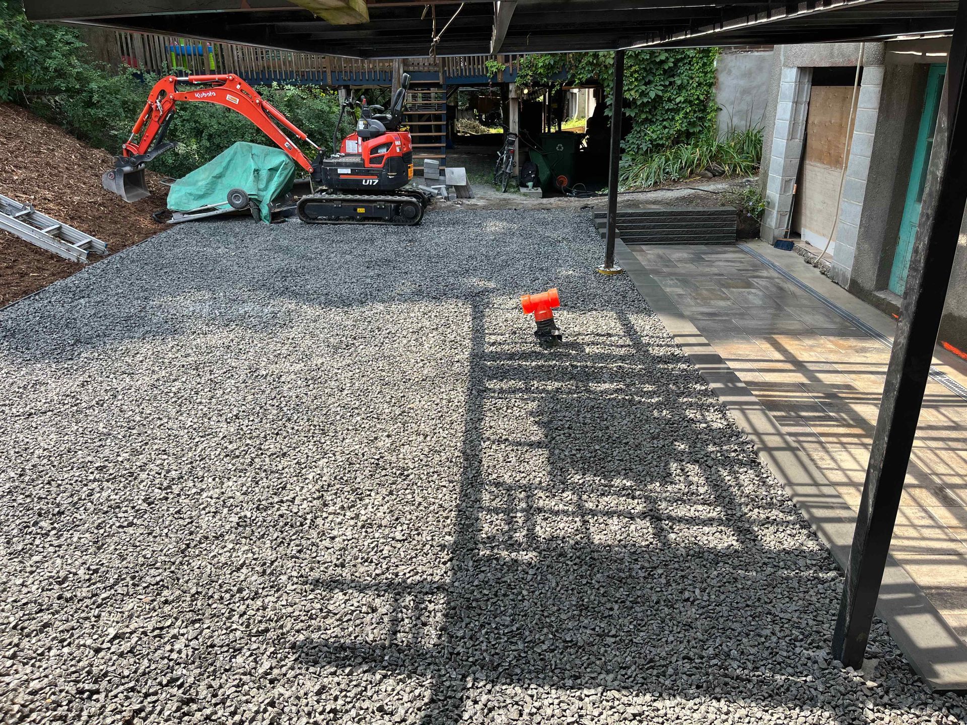 A gravel driveway with a small excavator in the background.