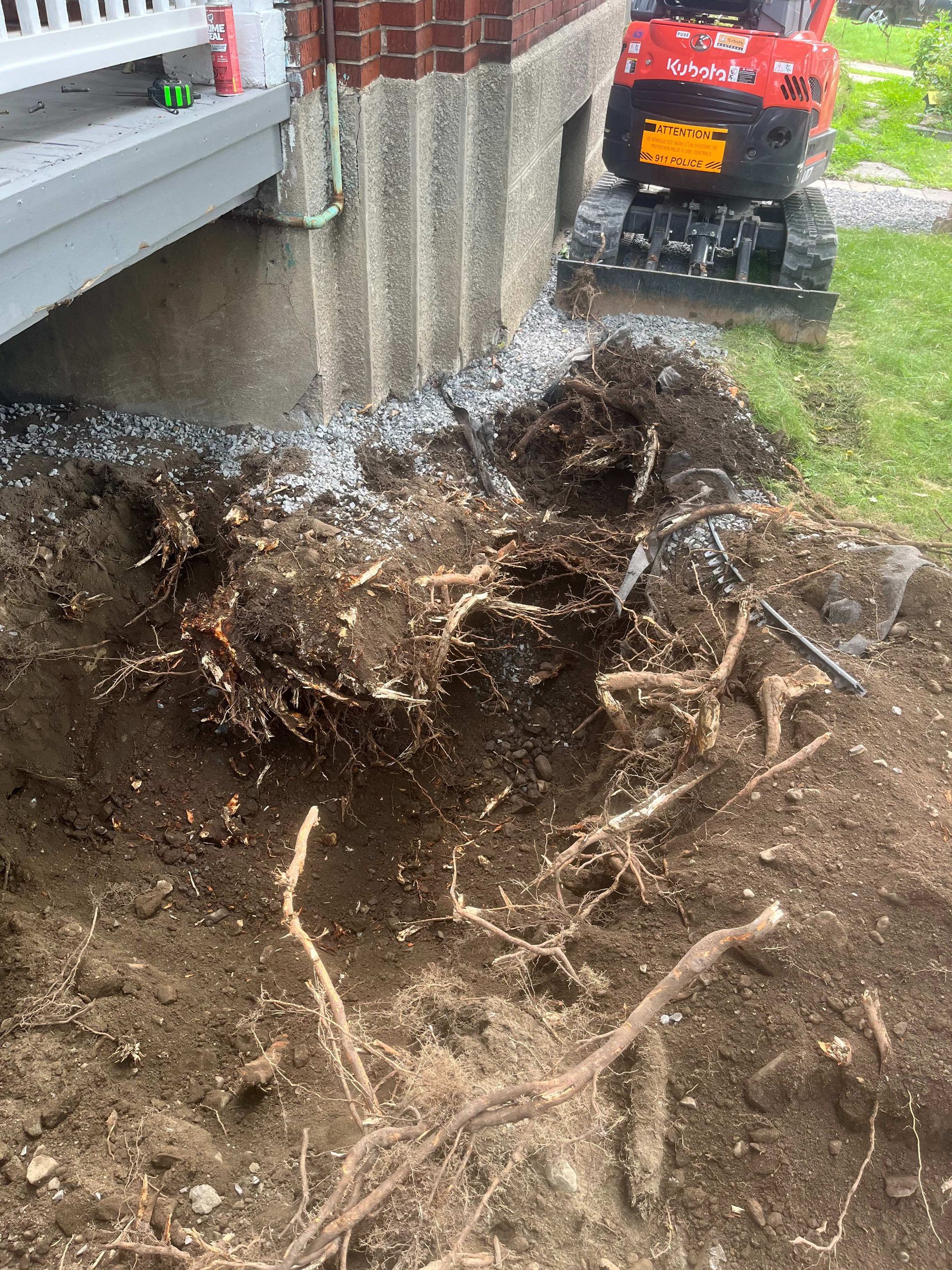 A large pile of dirt and roots in front of a house.