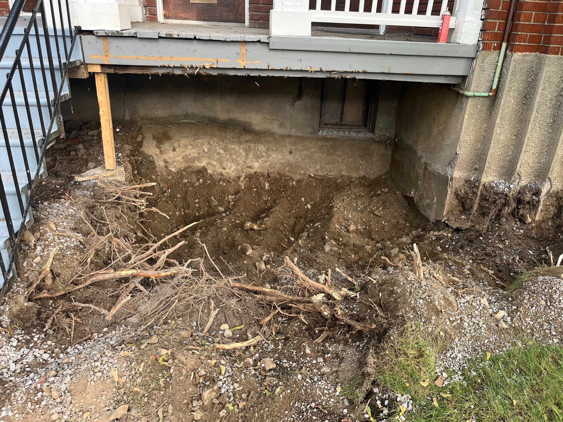 There is a hole in the ground in front of a house.