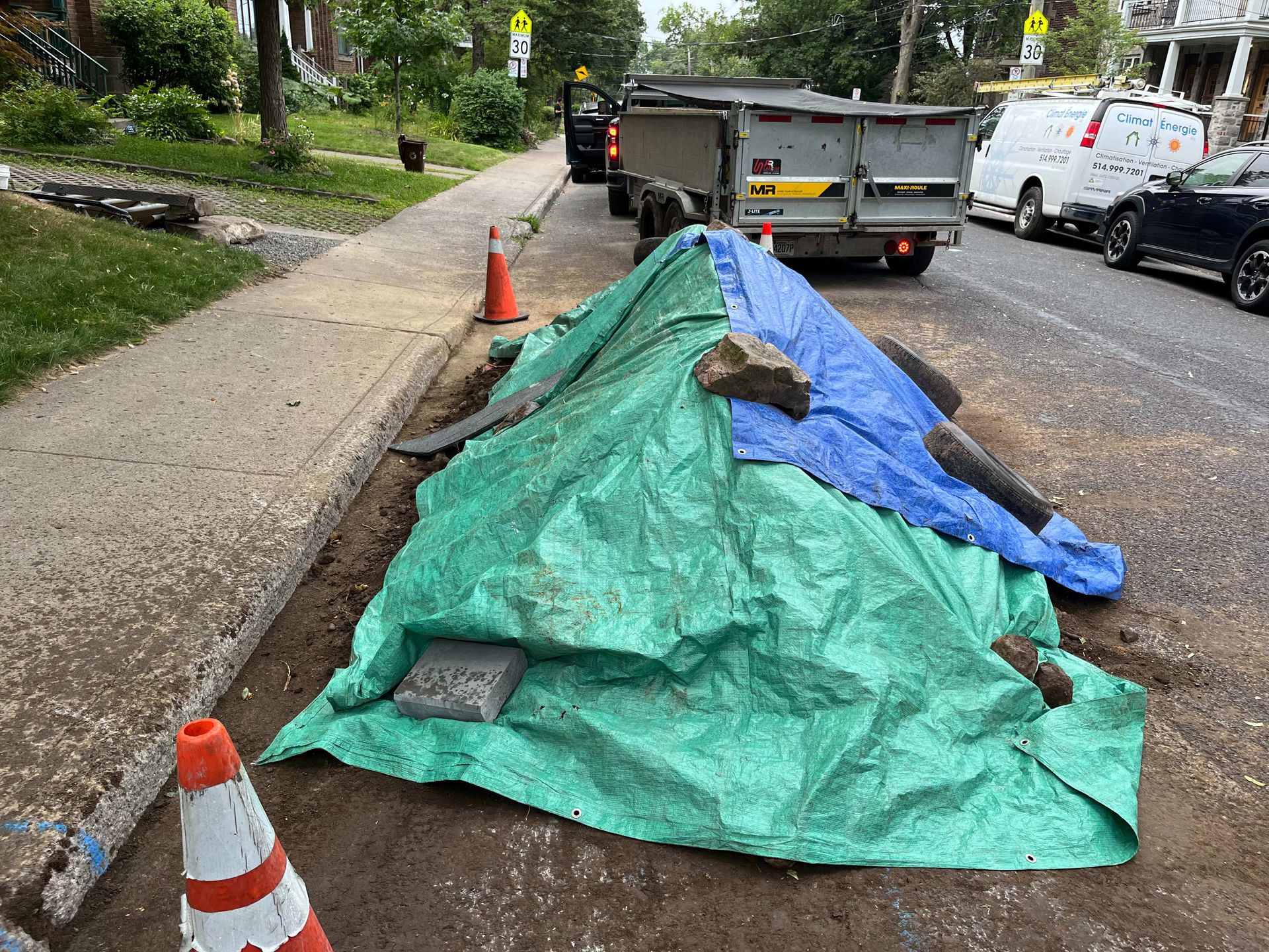 A green tarp is covering a pile of rocks on the side of the road.